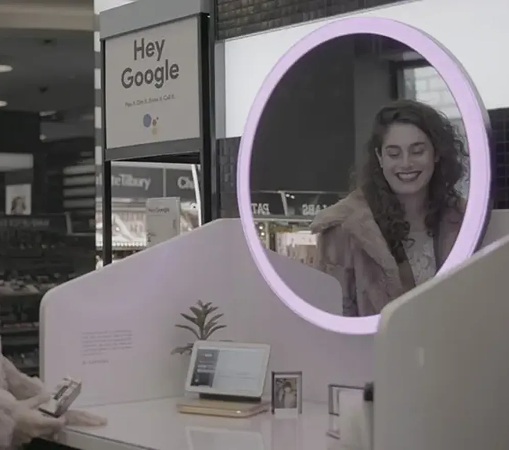 Guest interacts with a Google Home-inspired vanity installation featuring a large illuminated mirror and integrated smart display. Designed for a broad public audience, the experience uses familiar household settings and intuitive visual cues to encourage self-guided exploration, allowing visitors to discover products and technology naturally within the context of their everyday routines.