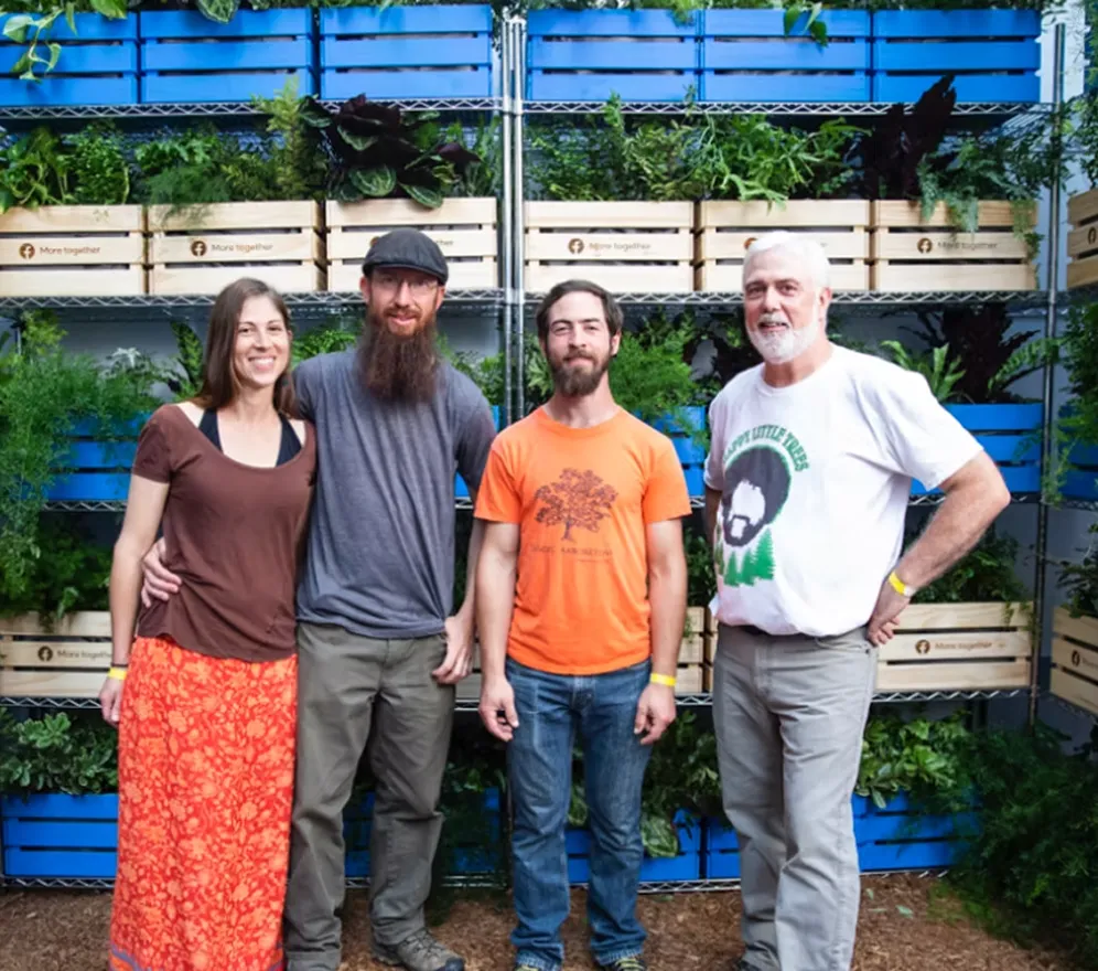 Community members pose together in front of a living wall of plants at a Facebook Groups activation celebrating environmental stewardship and shared interests.
