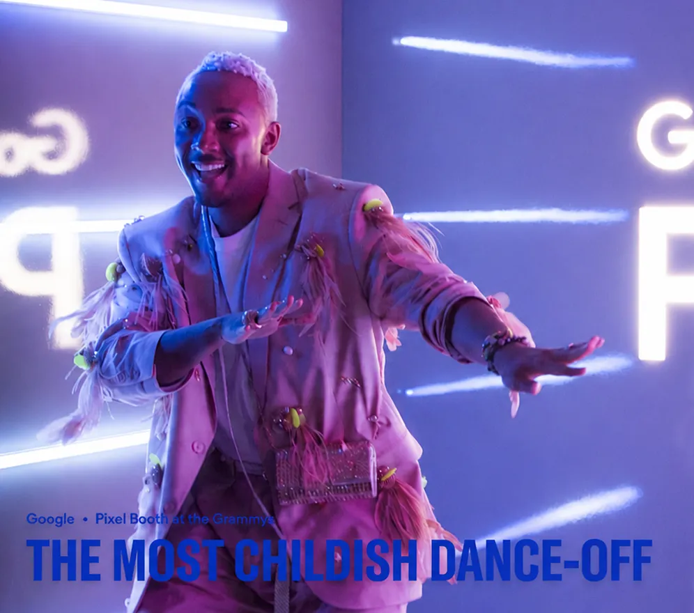 An event attendee performs playful dance moves inside a Google Pixel activation space illuminated by vibrant blue and purple LED lighting.
