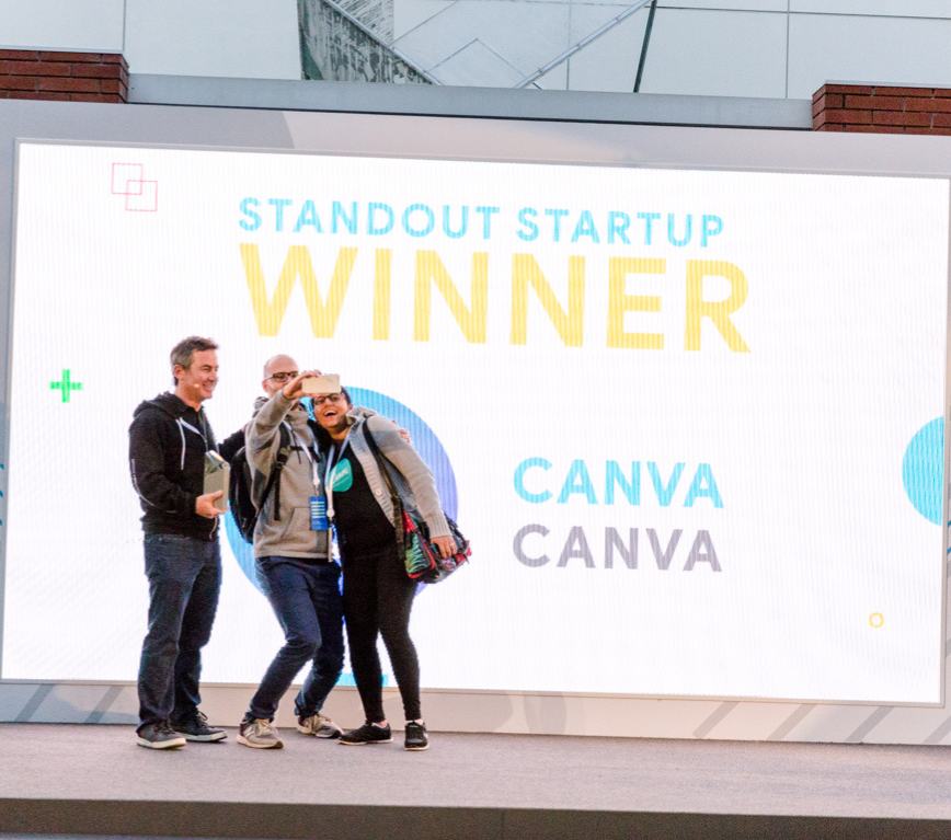 People taking a photo in front of the standout starter winner backdrop.